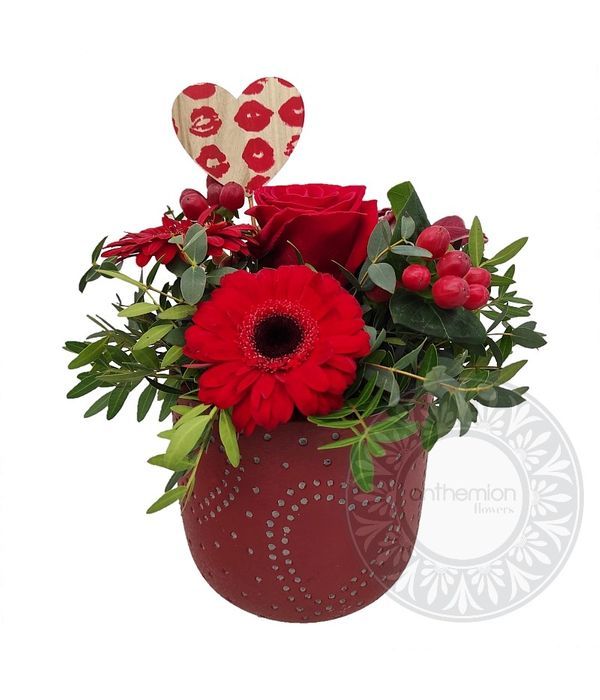Flower arrangement in red ceramic pot with hearts