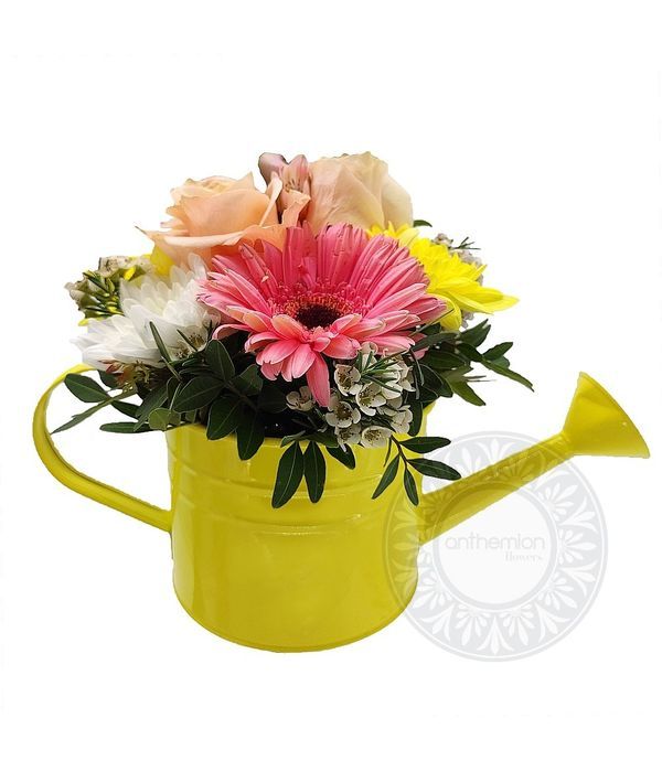 Yellow watering can with fresh flowers